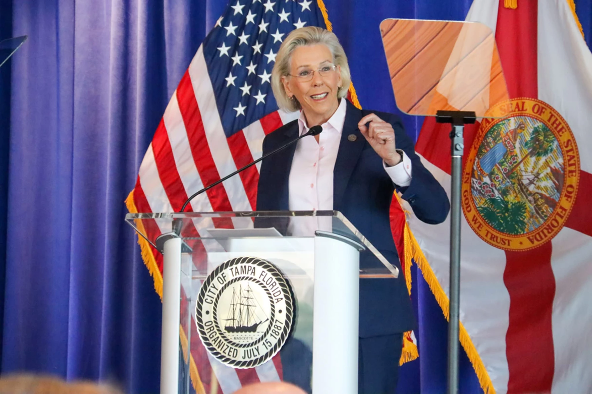 Tampa Mayor Jane Castor stands at a podium with the flags of the USA and the state of Florida behind her.